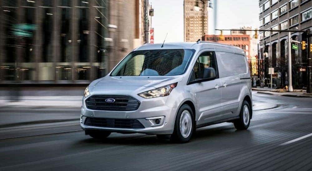 A silver Ford Transit Connect is shown diving in the street.