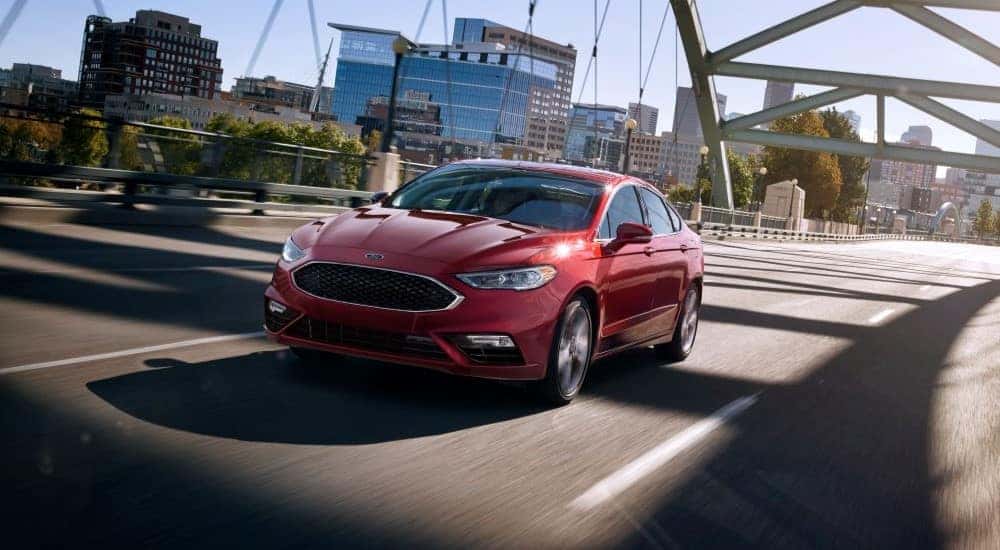 A red 2017 Ford Fusion is shown driving over a bridge.