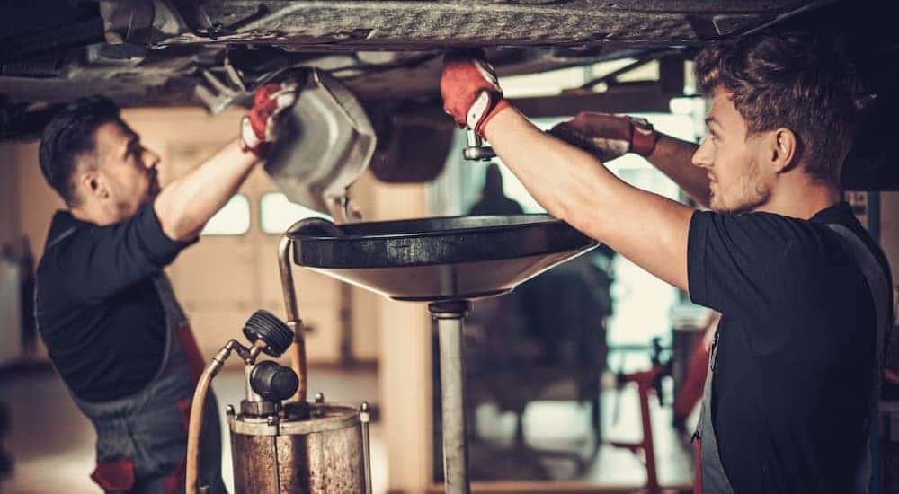 Two mechanics completing an oil change is shown.