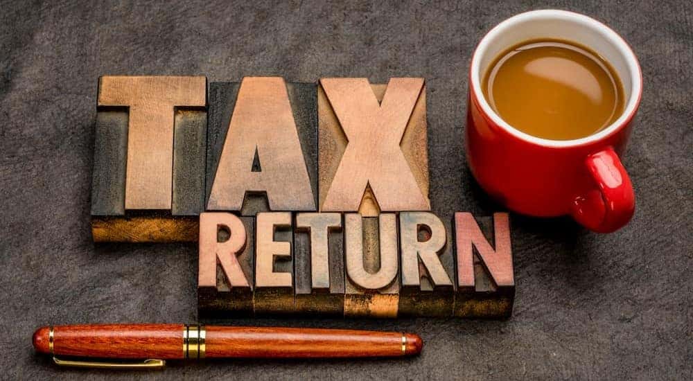 A tax return reminder is shown beside a pen and a coffee cup.