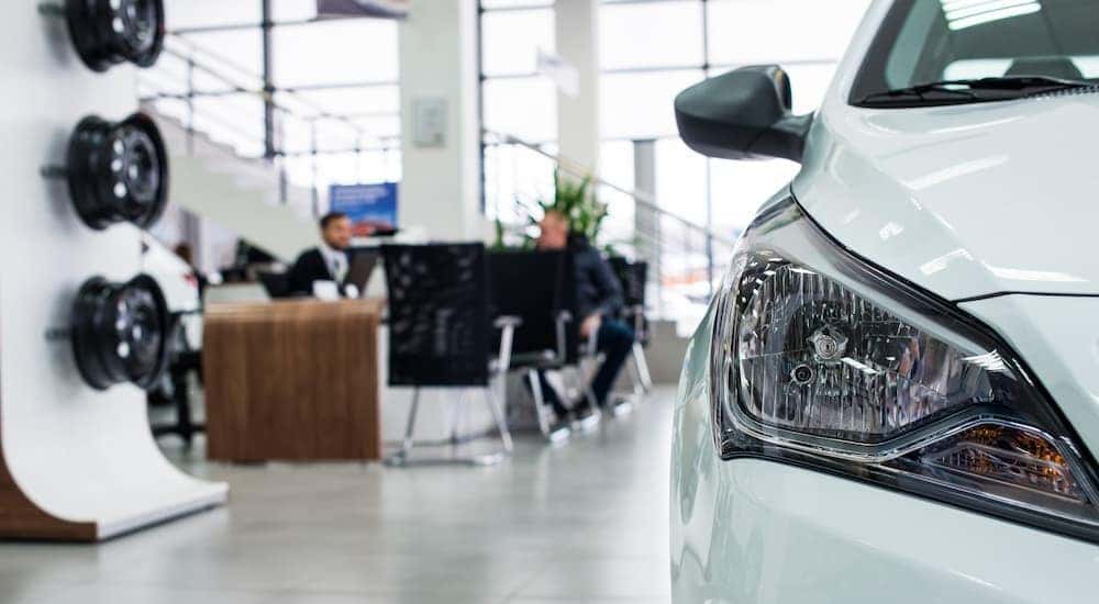 A cars headlight is shown in a dealerships showroom.