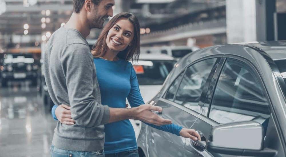A couple is shown looking at cars at a dealership.