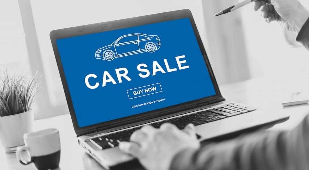 A person using their laptop to car shop online is shown.