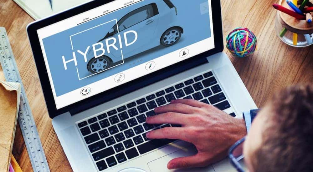 A man using a laptop to car shop online is shown.