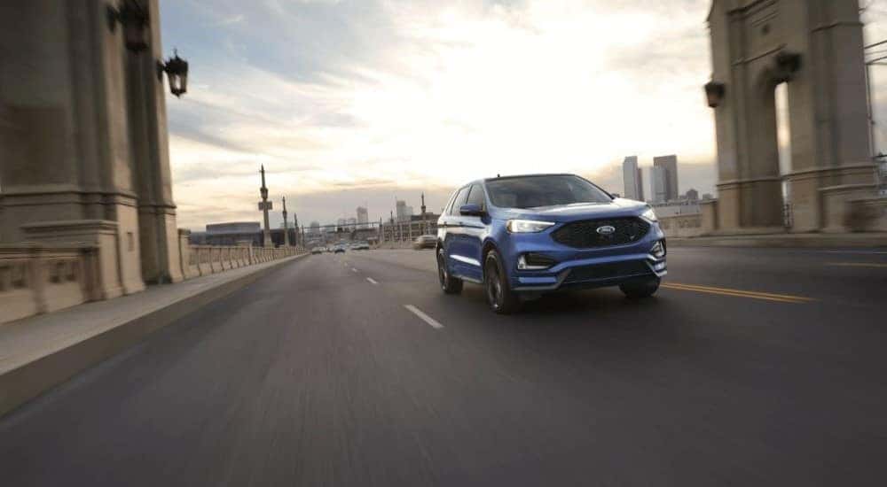 A blue 2021 Ford Edge is shown driving on a highway.
