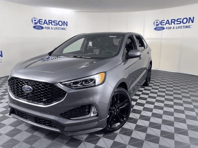A silver 2021 Ford Edge is shown parked in a showroom.