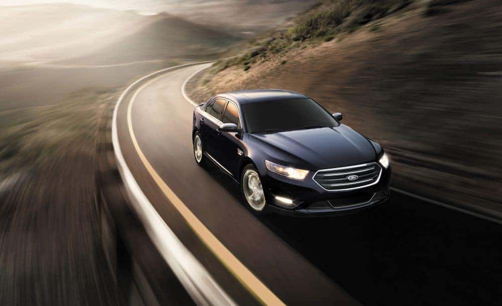 A black 2014 Ford Taurus Limited is shown rounding a corner.