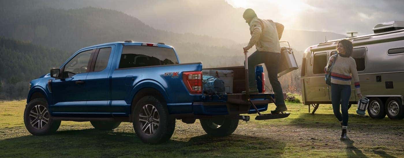 A person is shown unloading a blue 2022 Ford F-150 after visiting a local Ford dealership.