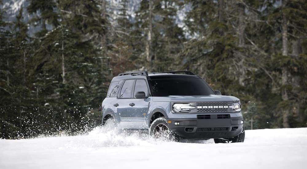 A grey 2022 Ford Bronco Sport is shown kicking up snow in a field.