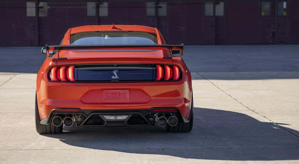 An orange 2022 Ford Mustang GT500 is shown from the rear after leaving a Ford dealership.