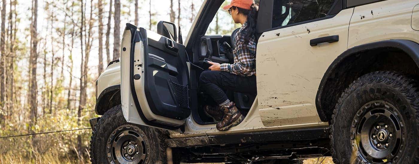 A cream colored 2022 Ford Bronco Everglades is shown off-roading on a muddy path.