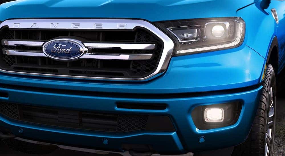 A close up shows the driver side headlight and grille on a blue 2022 Ford Ranger.
