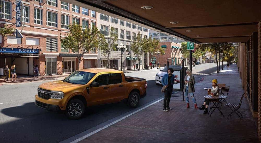 A gold 2022 Ford Maverick is shown on a city street after leaving a Carmel Ford dealer.