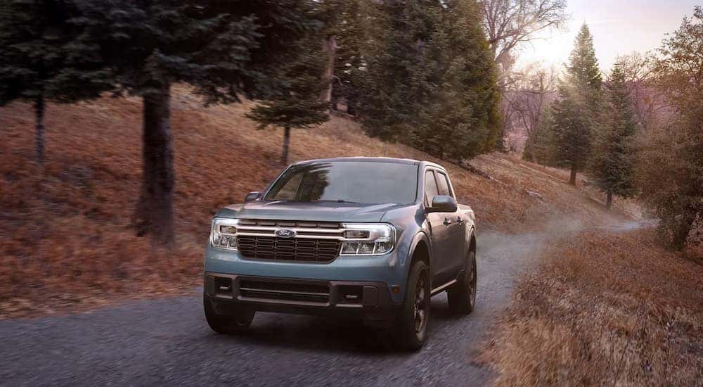 A blue 2022 Ford Maverick is shown driving on a dirt road.