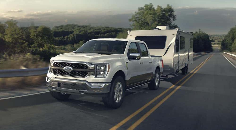A white 2022 Ford F-150 Limited is shown towing a trailer.
