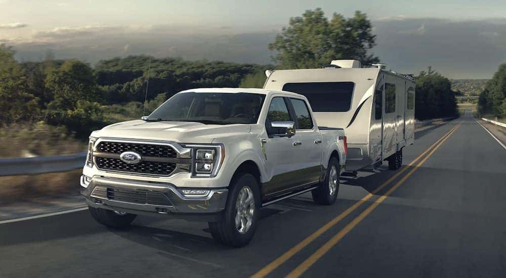 A white 2022 Ford F-150 is shown from the front towing a trailer.