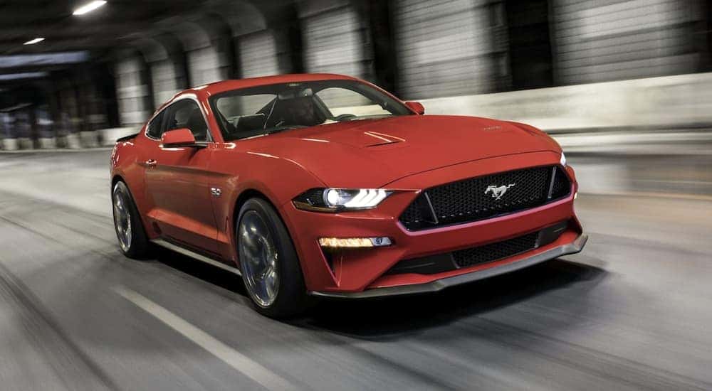 A red 2022 Ford Mustang is shown from the front driving on an open road after leaving a Ford dealership near you.