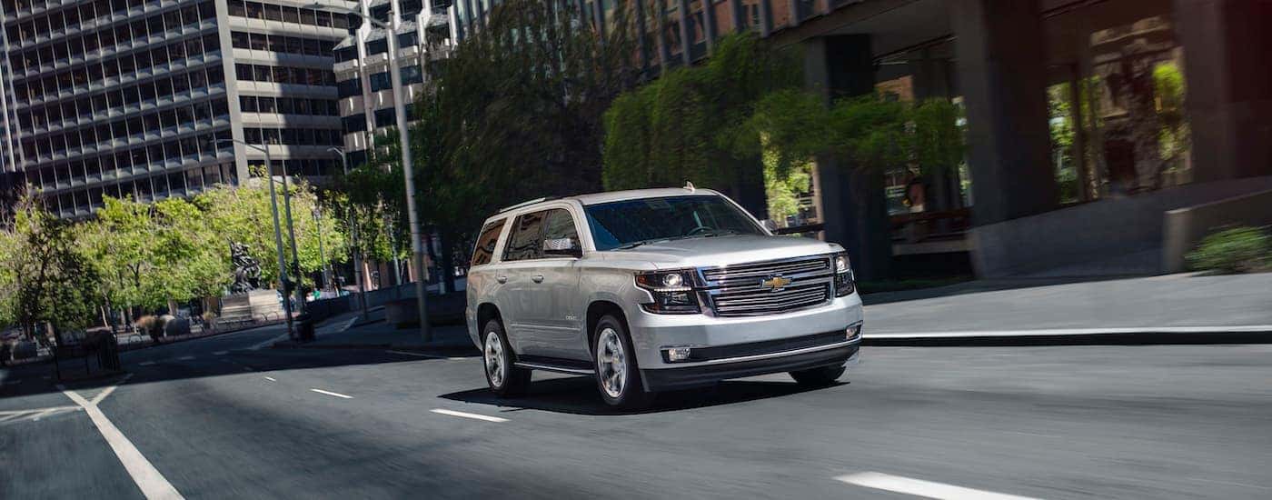 A silver 2020 Chevy Tahoe, a popular used car for sale, is shown driving on a city street.