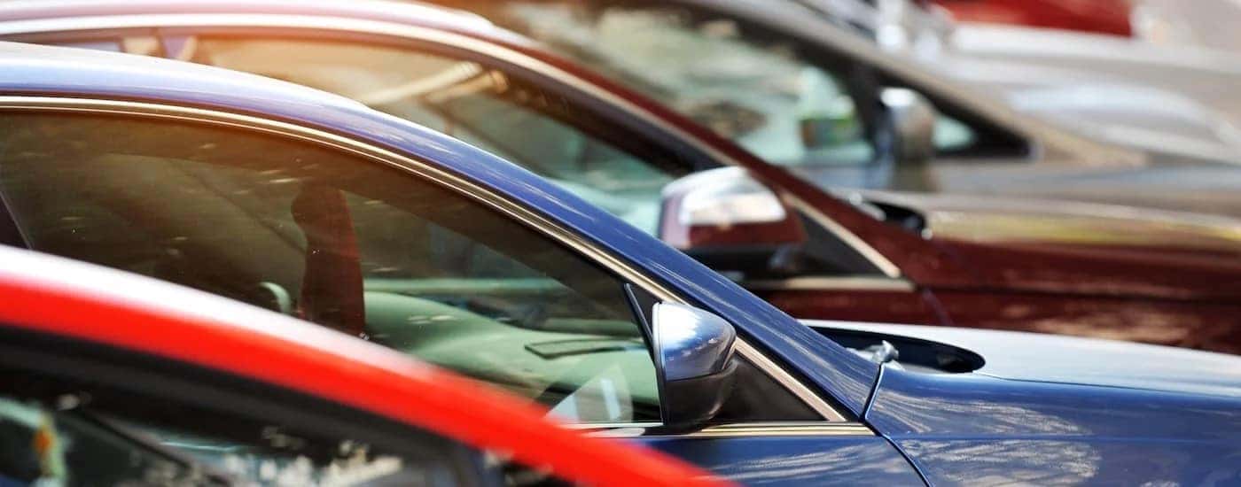 A row of used cars is shown at a used car dealer.