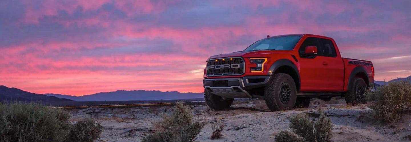 Red 2019 Ford Raptor parked in front of Purple and Pink Sunset