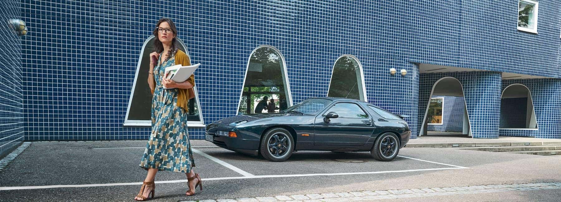 Woman walking away from a parked Porsche 928