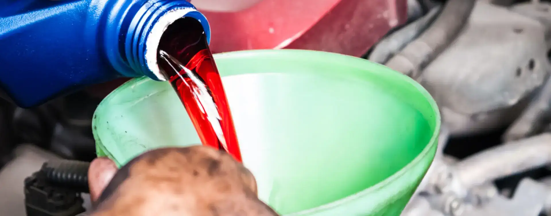 Mechanic pouring transmission fluid into a funnel