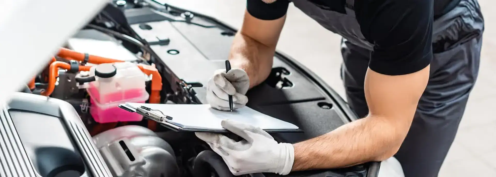 Mechanic with a clipboard looking at an engine