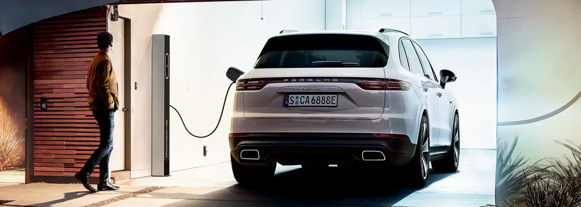 Rear view of a white Porsche Cayenne charging