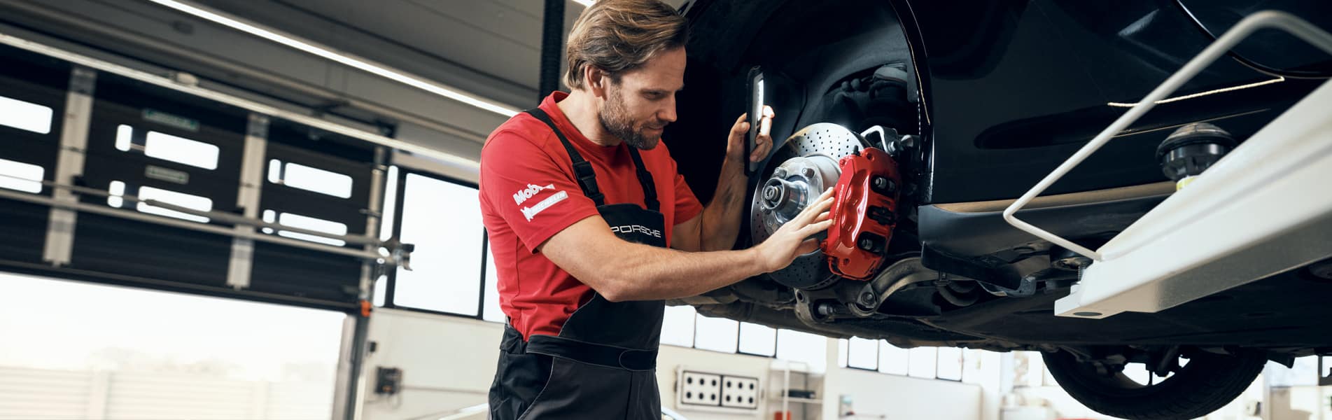 A certified Porsche technician working on a vehicle's brakes