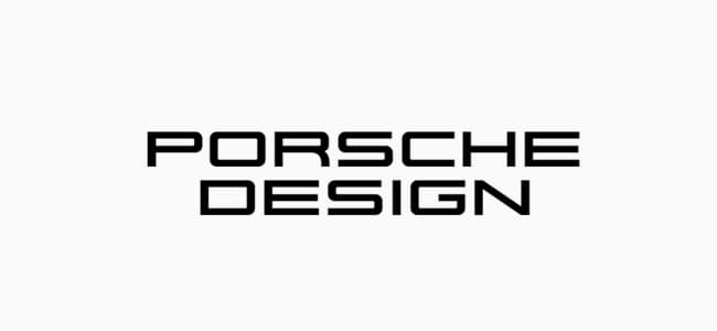 Two men leaning against a Porsche coupe wearing Porsche Design clothing