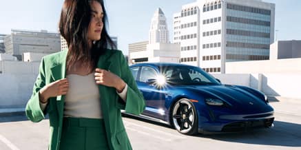 A woman walking away from a blue Porsche in a parking spot