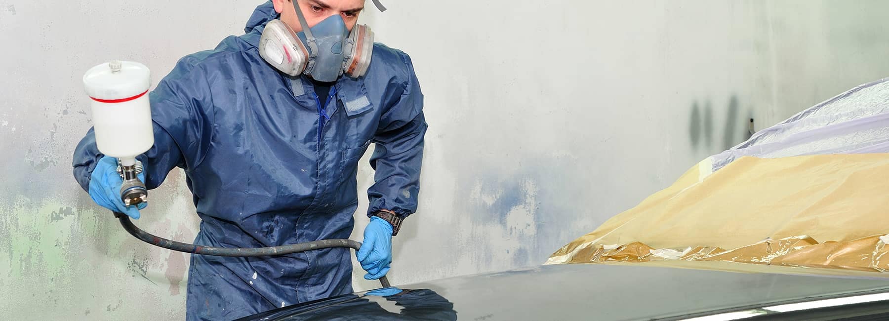 technician sprays new coat of paint on car
