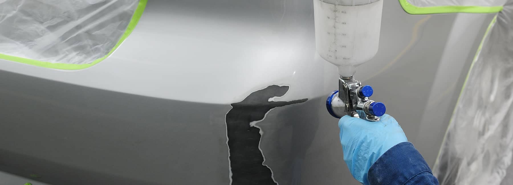 technician gets ready to spray paint on car body repair