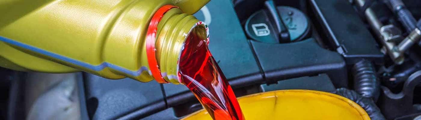 Close up view of a red liquid being poured into a vehicle engine