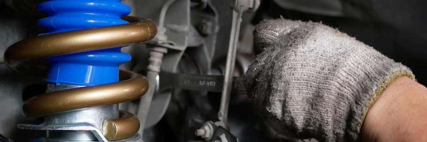 Close up view of a service tech working on a vehicle's suspension