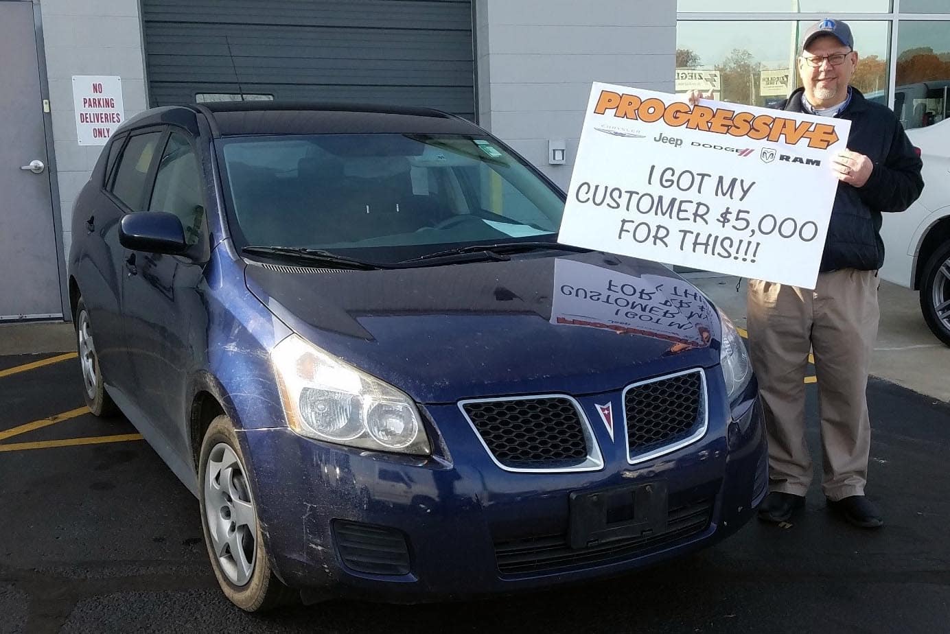 smiling Progressive customer next to the trade-in Pontiac sedan they received $5000 for
