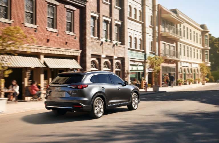 rearview of gray mazda cx-9 driving by buildings