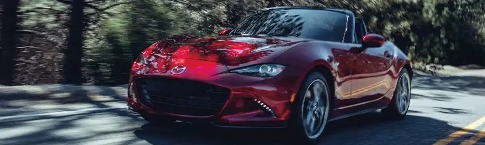 red 2021 Mazda MX-5 Miata driving through forest