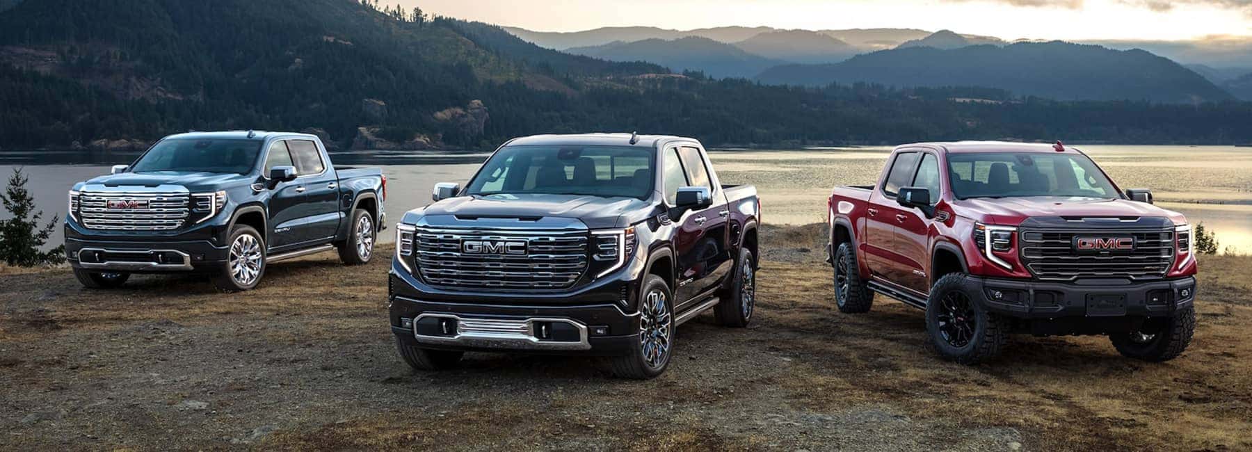 Three 2023 Sierra 1500 trucks parked near river