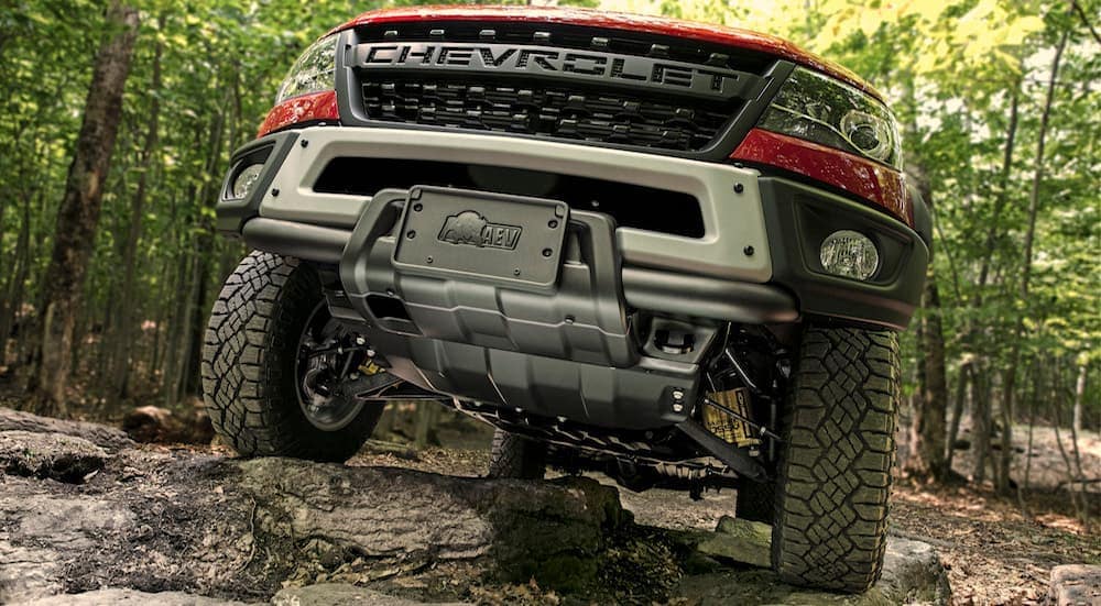 A red 2020 Chevy Colorado Bison is driving over large rocks in the woods.