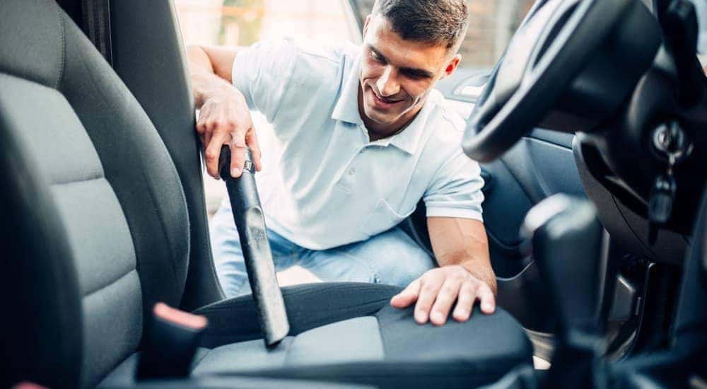 A man is preparing for his end of lease turn-in by vacuuming his car.