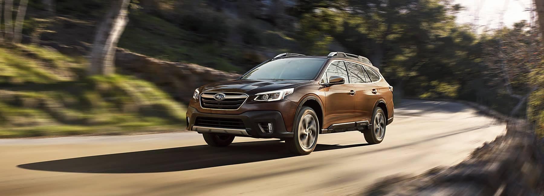2022 Subaru Outback side 3 quarter driving down forest road