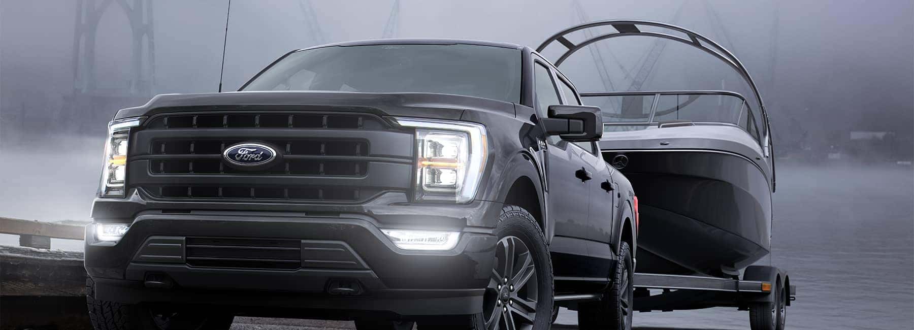 A black 2021 Ford F150 backing a boat in to a lake on a dock