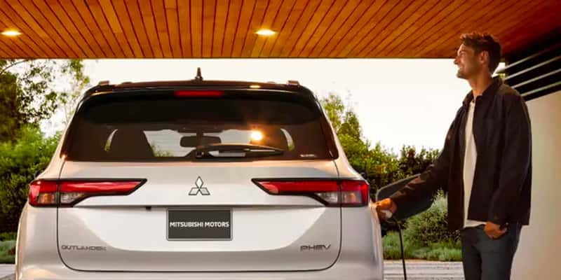 a man plugging in the 2025 Mitsubishi Outlander PHEV.