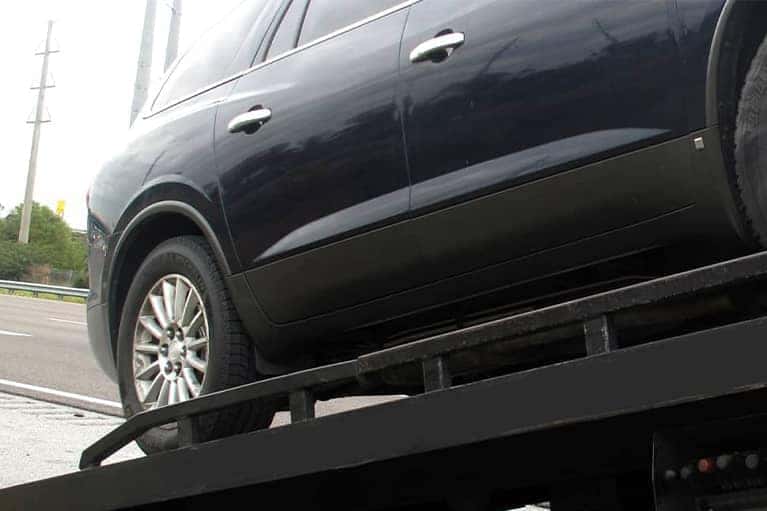 A black car being towed on a flatbed tow truck_mobile