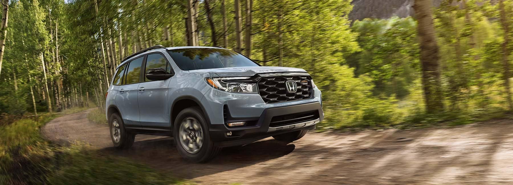 Sonic Gray Pearl 2022 Honda Passport driving through the forest