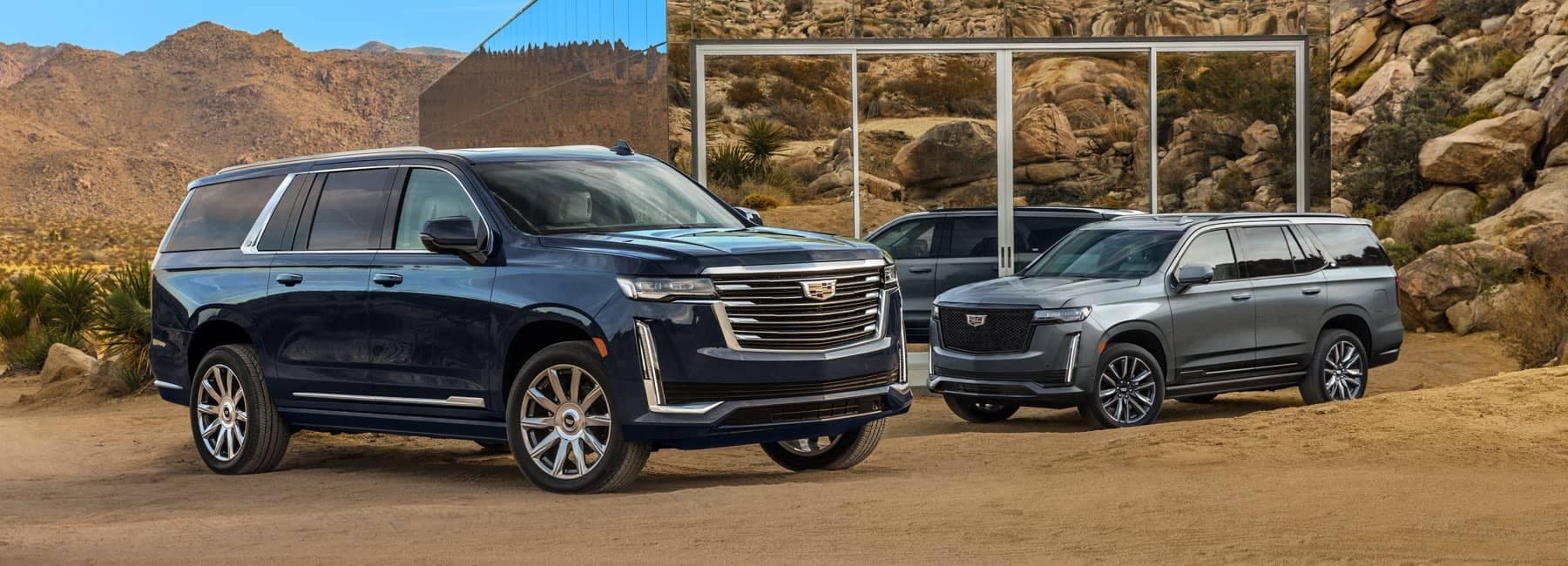 Two 2021 Cadillac Escalades parked in front of a glass house