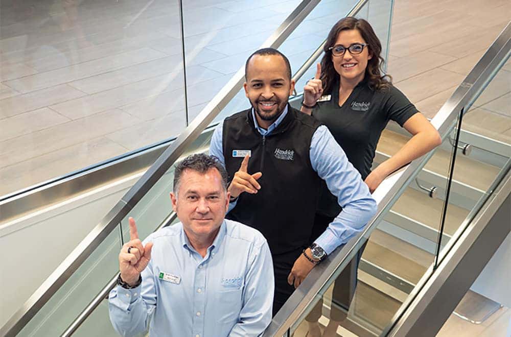 Smiling employees are shown on a stair case.