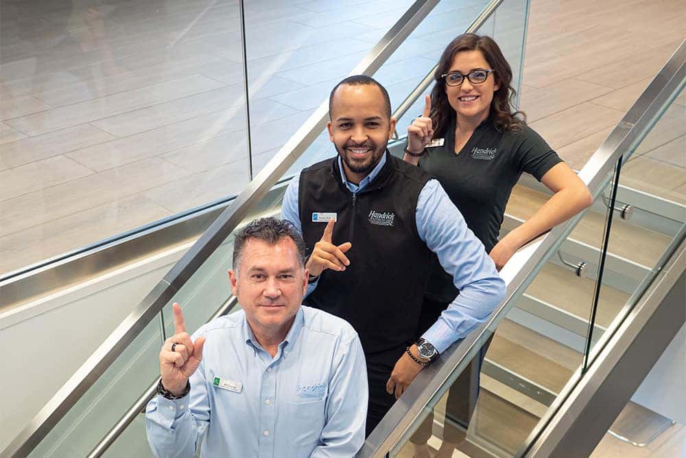 Smiling employees are shown on a stair case.