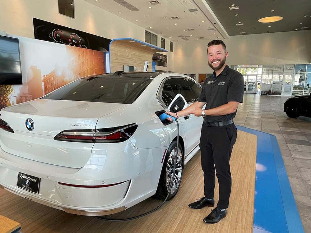 A smiling employee is shown charging a BMW.